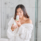 IN THE PICTURE - A BEAUTIFUL WOMAN IN A BATHROOM SMELLING THE TIARA CUCUMBER AND MELON NATURAL DEODORANT WITH THE LID ON HER HAND IN A BATHROBE  - NATURAL DEODORANT MELON AND CUCUMBER